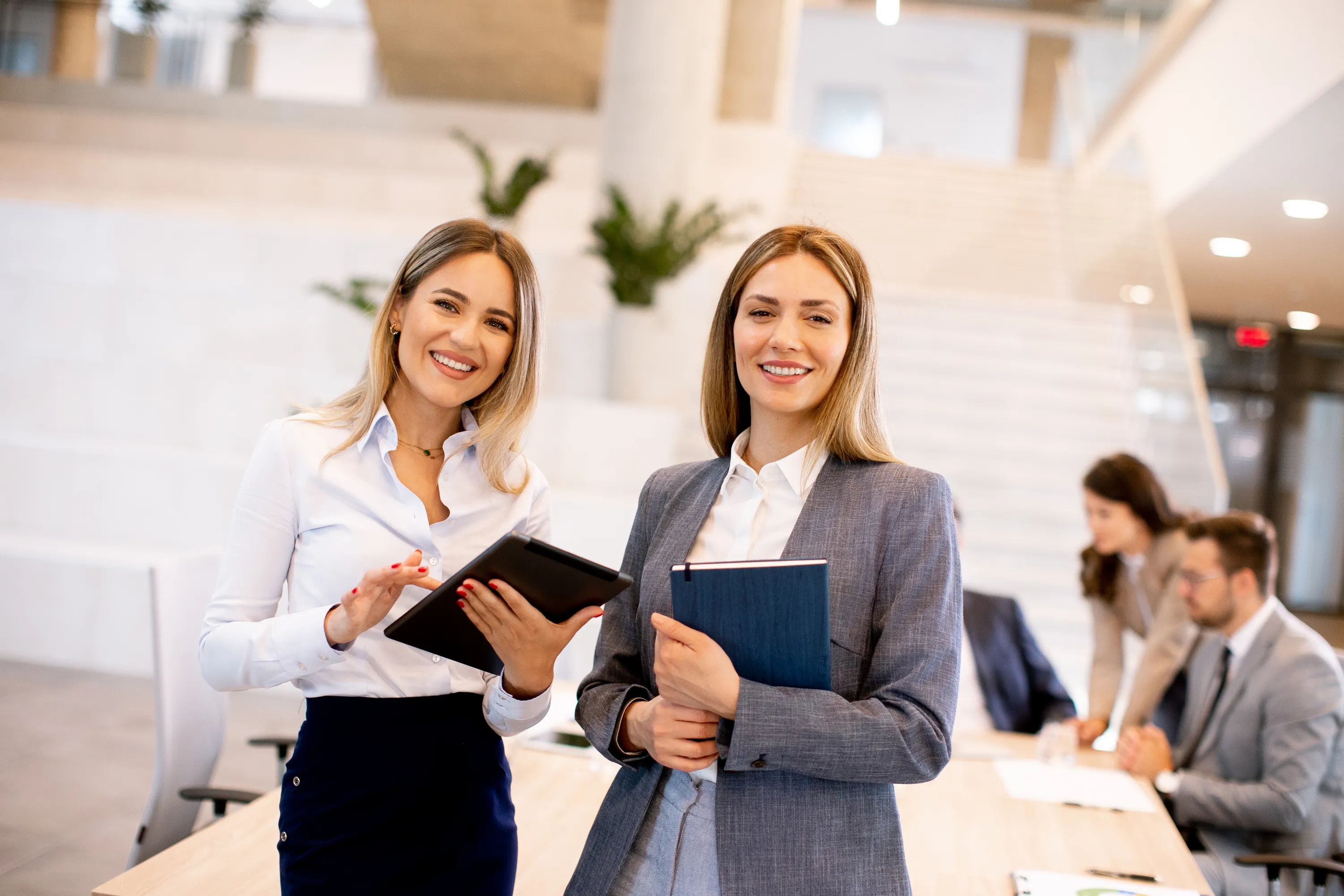 Two business women holding computers in their hands